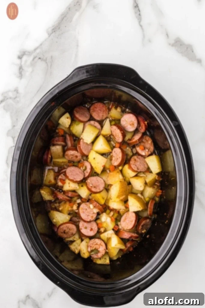 Slow-Cooker Sausage and Potato Delight 13 Full crockpot with ingredients for slow cooker sausage and potatoes.