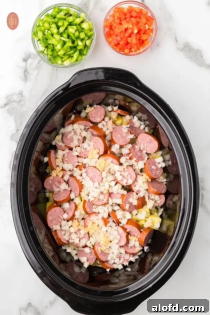 Slow-Cooker Sausage and Potato Delight 8 Crockpot filled with cubed potatoes, sausage, onion, bell peppers, and garlic.