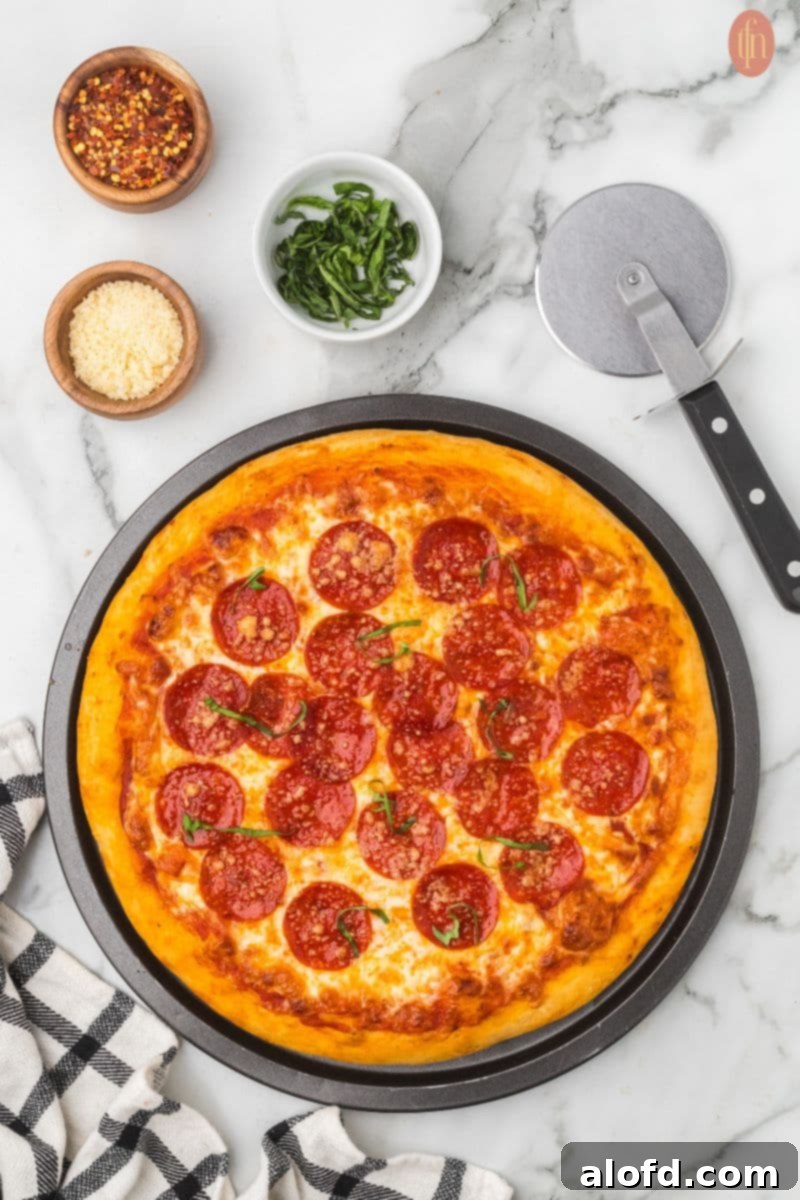 Homemade Pizza with a Crust Made from Scratch 2 Homemade pizza with pepperoni, seasonings, and a pizza cutter.