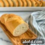 A cut loaf of French bread with slices in the background.