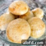Perfectly baked batch of sourdough hamburger buns in a glass serving dish.