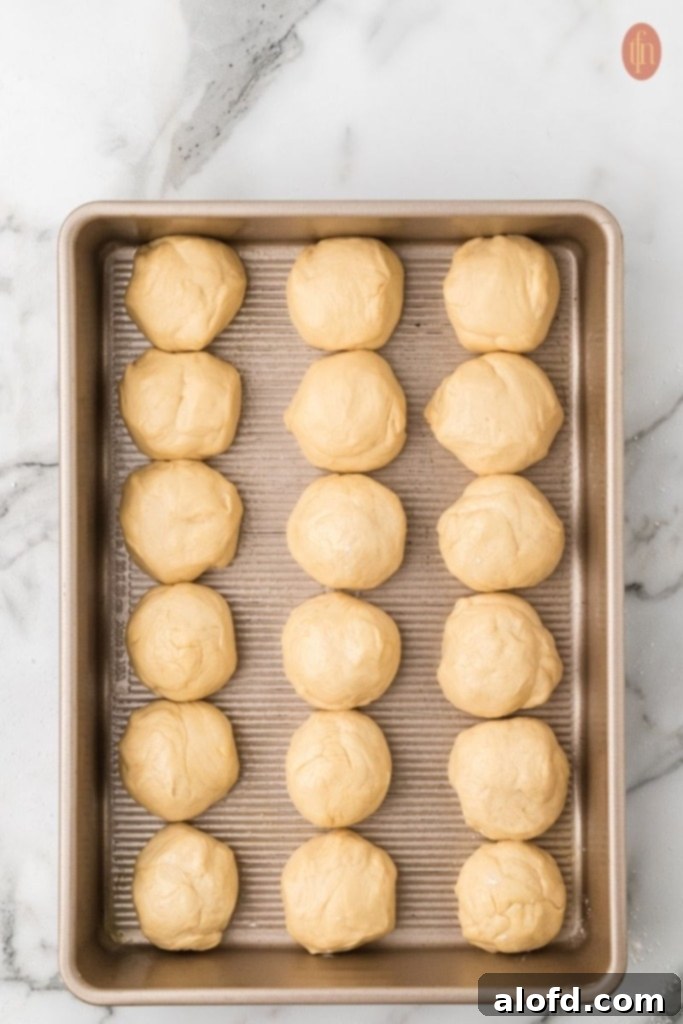 Quick Dinner Rolls 11 Unbaked dinner rolls on a gold baking pan.