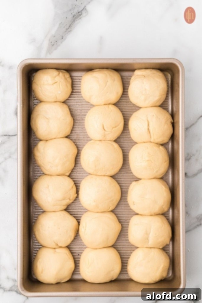 Quick Dinner Rolls 12 Unbaked dinner rolls on a gold baking pan.